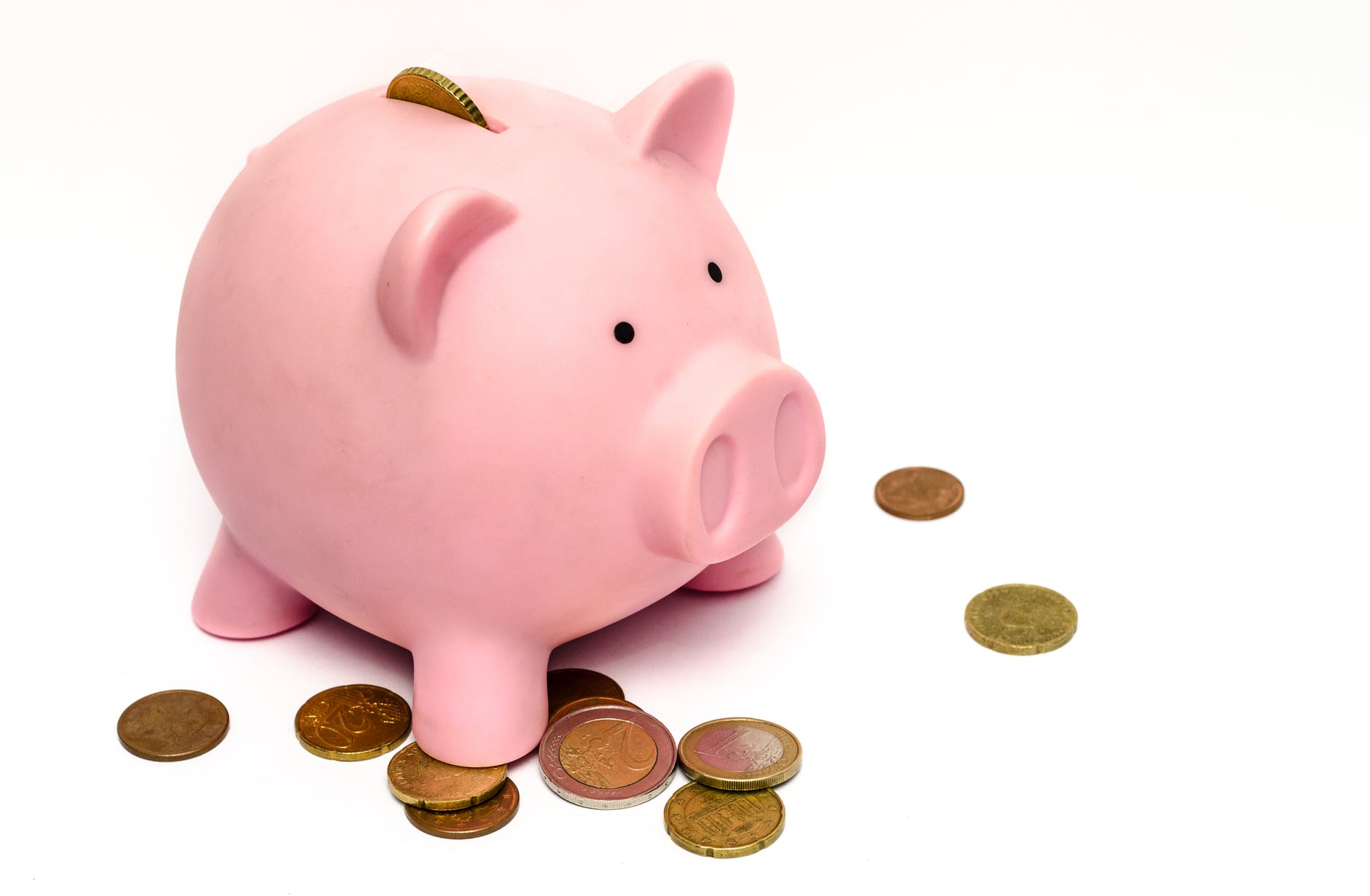 A piggy bank with coins around it on a white table