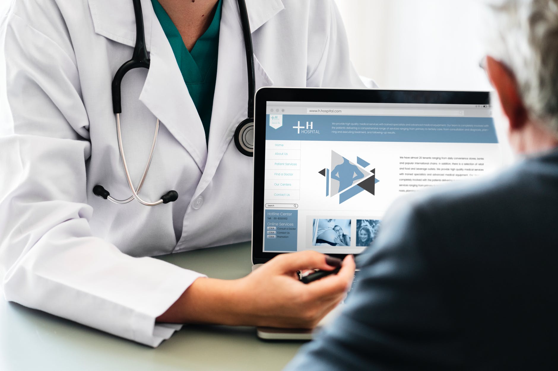 A doctor in a white coat showing a website to a patient