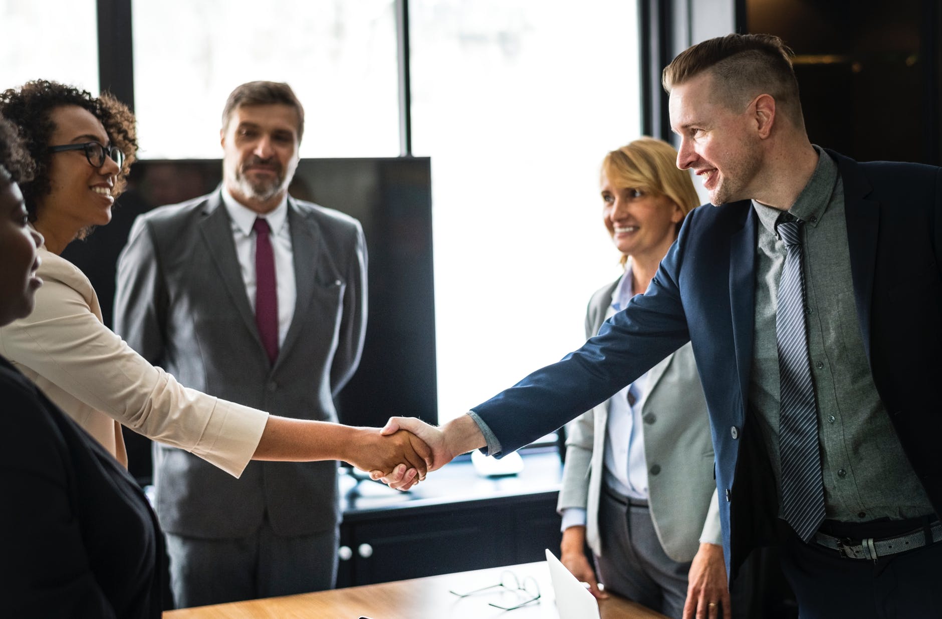 Clients and associates shaking hands after making a deal in an office setting