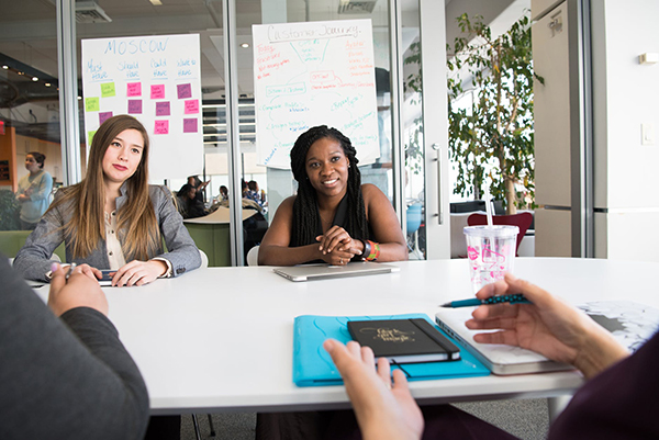 A meeting at a white desk with notebooks on it