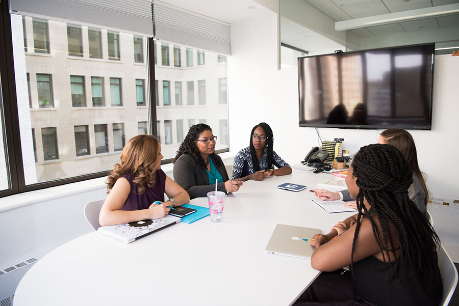 Women in a meeting room around a white table and a TV