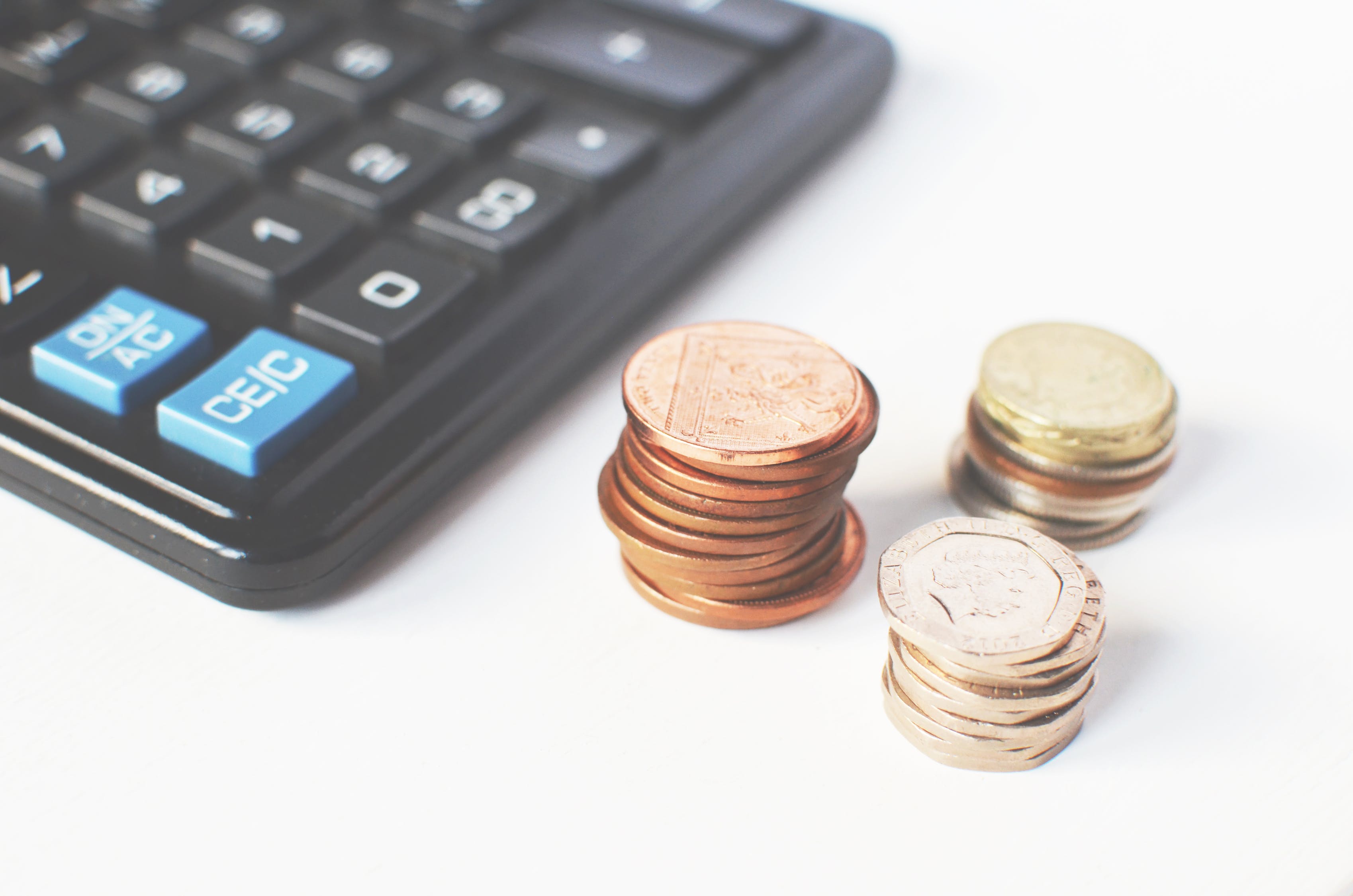 Stacks of coins on a white table next to a keyboard