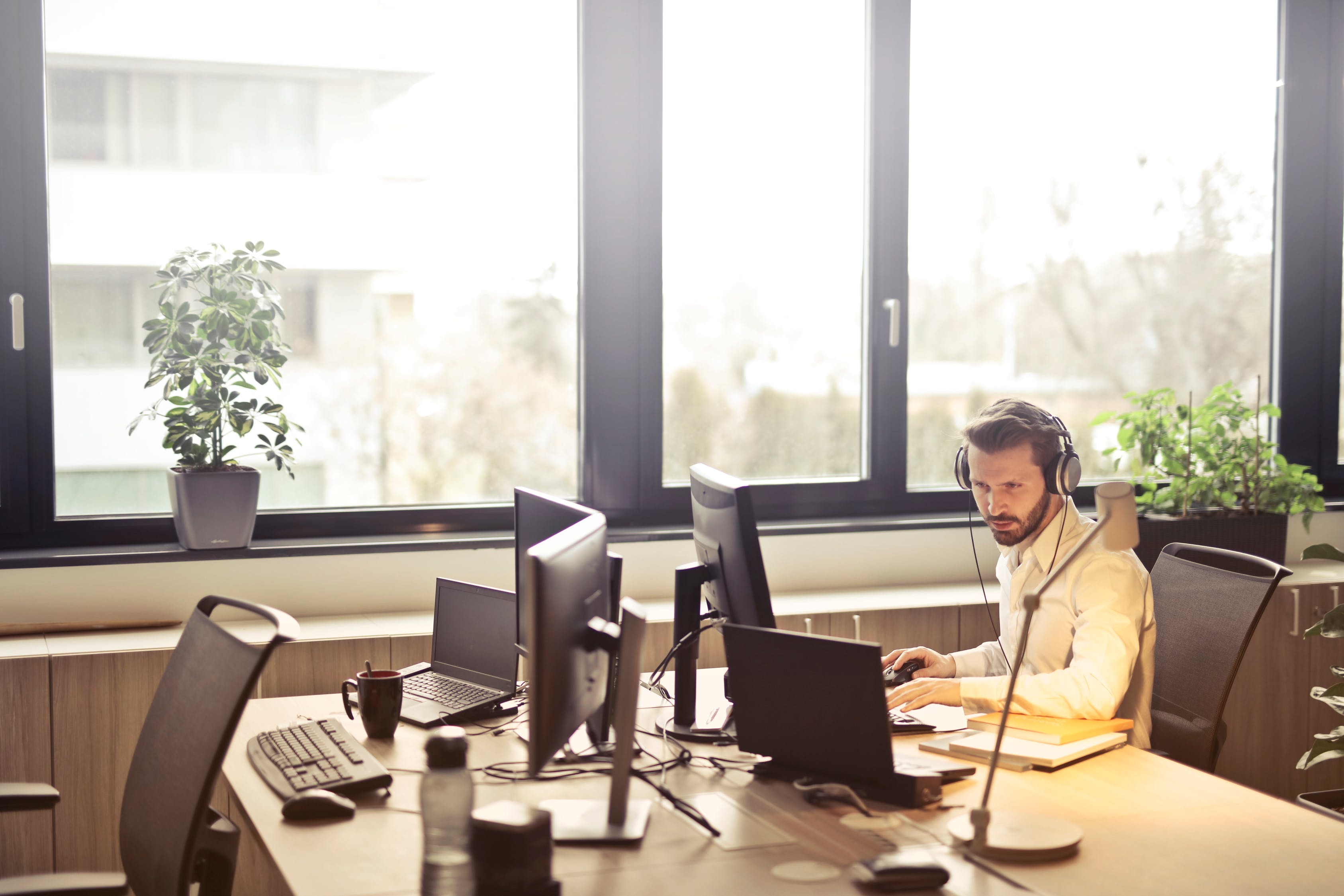 A man alone at a desk full of computers wearing headphones