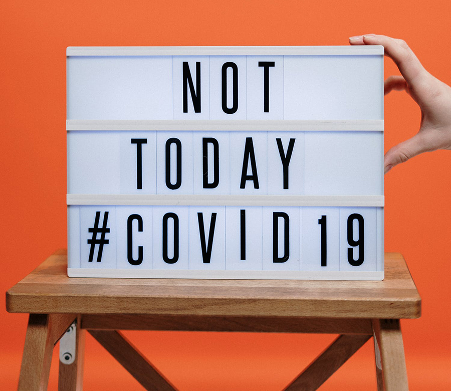 A desk sign with the words Not today Covid19 near an orange wall