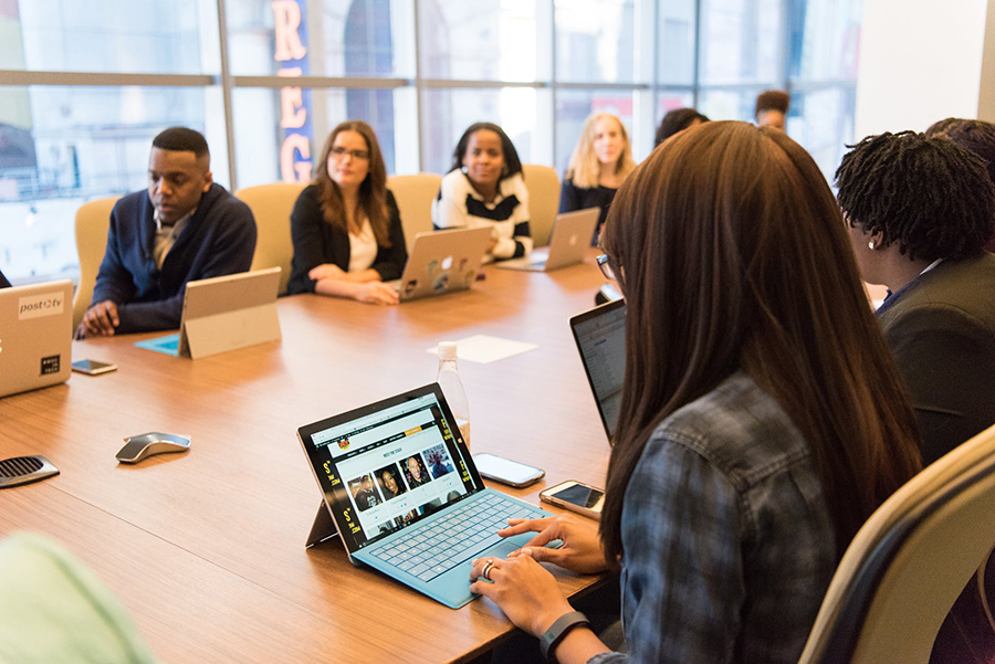 Colleagues around a table in a meeting with laptops