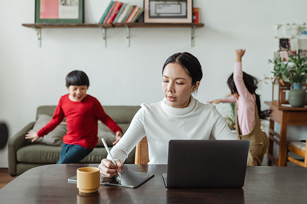 A woman trying to work from home with children playing in the background