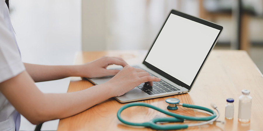 Doctor with a stethoscope typing on a computer