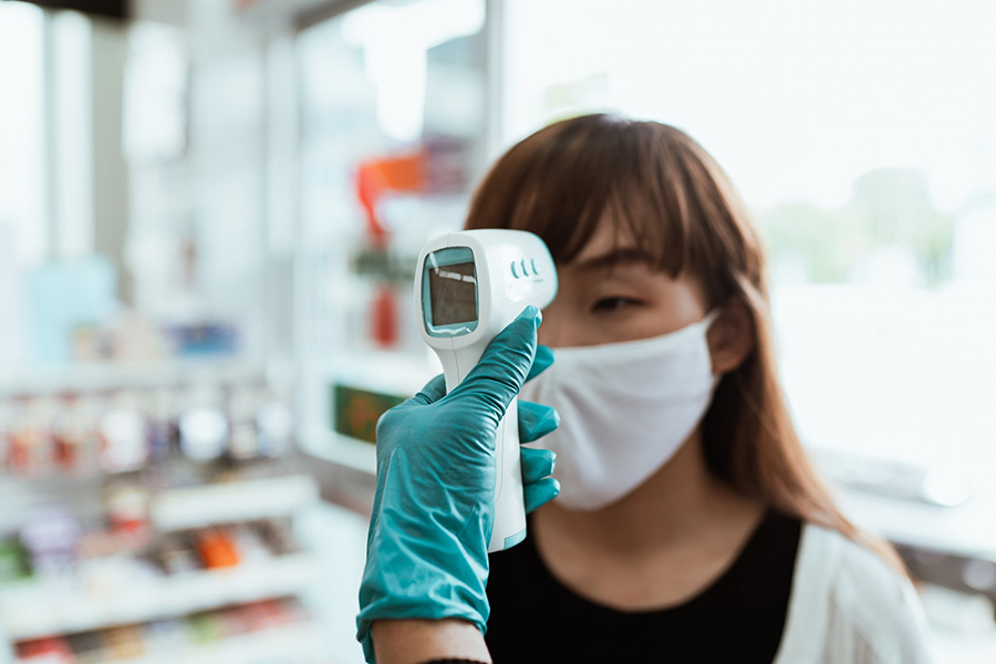 Woman in a face mask getting a forehead temperature test