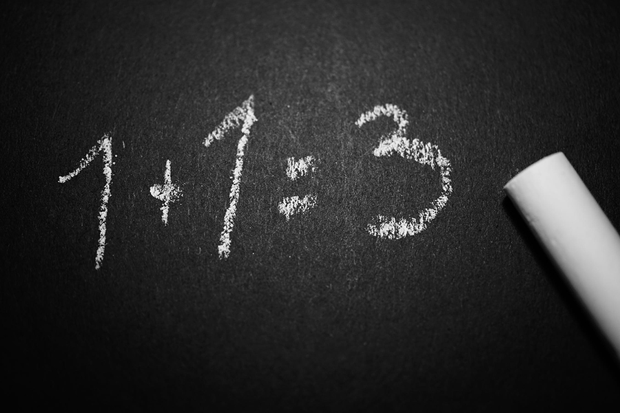 One plus one equals three written on a blackboard with chalk