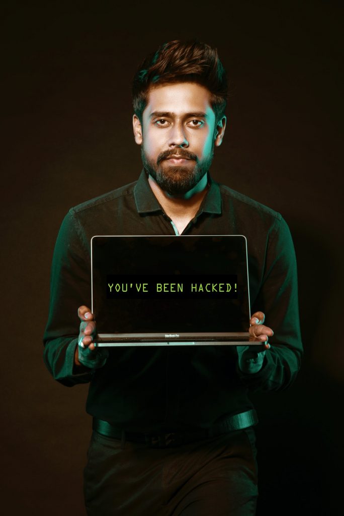 Man holding a laptop that says You've been hacked