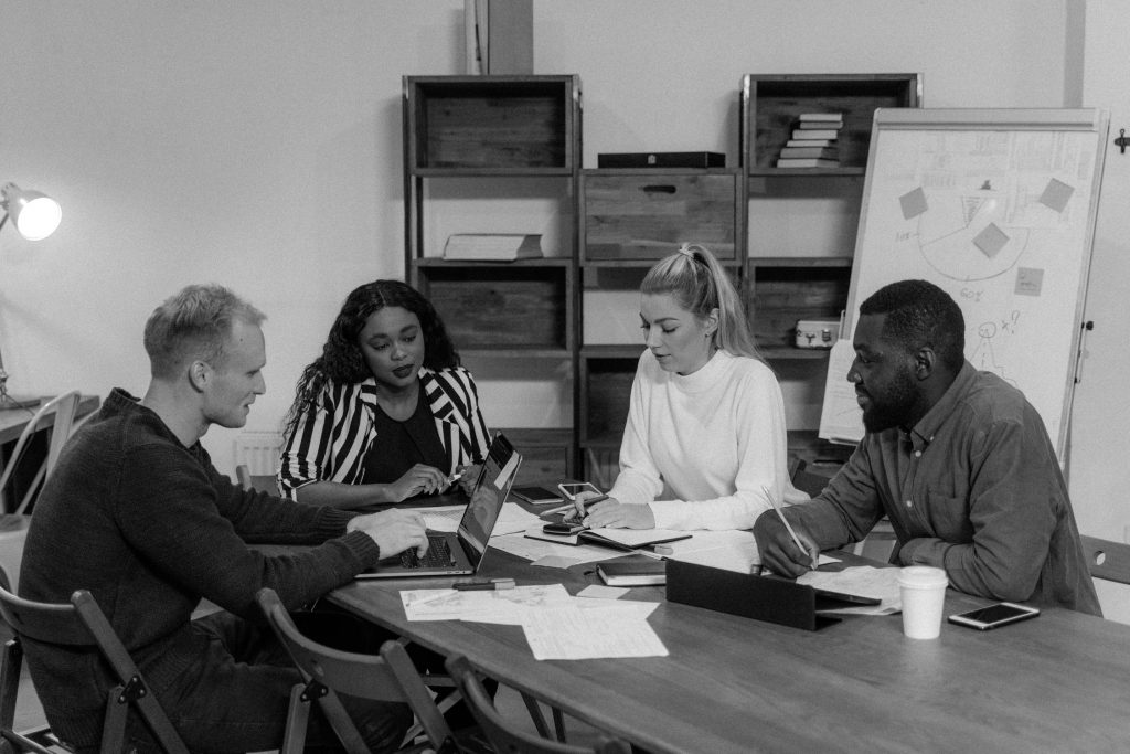 Black and white image of colleagues working on a wooden table