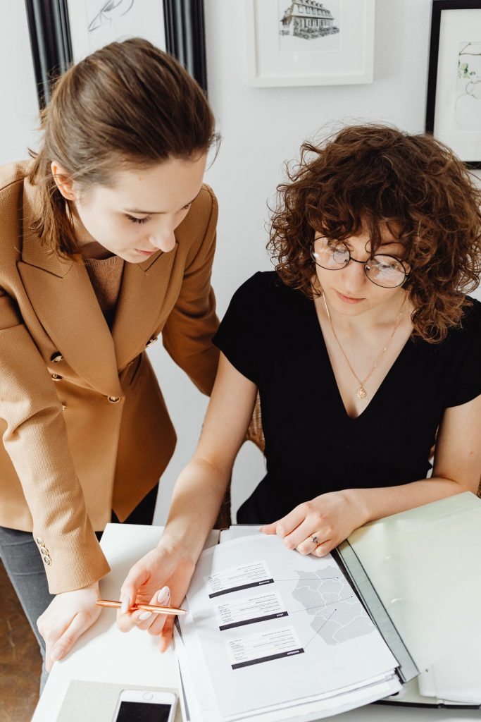 Two women discussing documents in a notebook