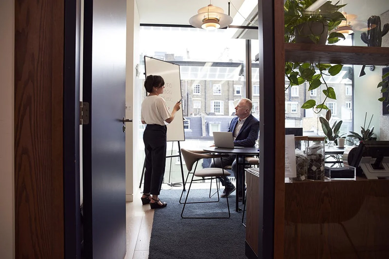 Man listening to a woman with a whiteboard in an office