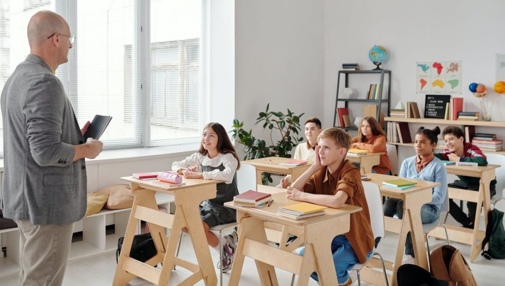Children at school learning from a teacher on wooden desks