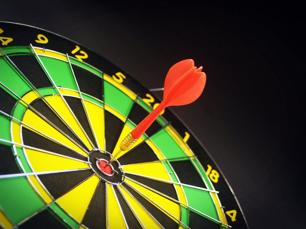A red dart hitting the bullseye on a dart board