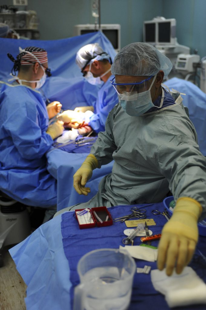 Three surgeons operating on a patient under a blue sheet