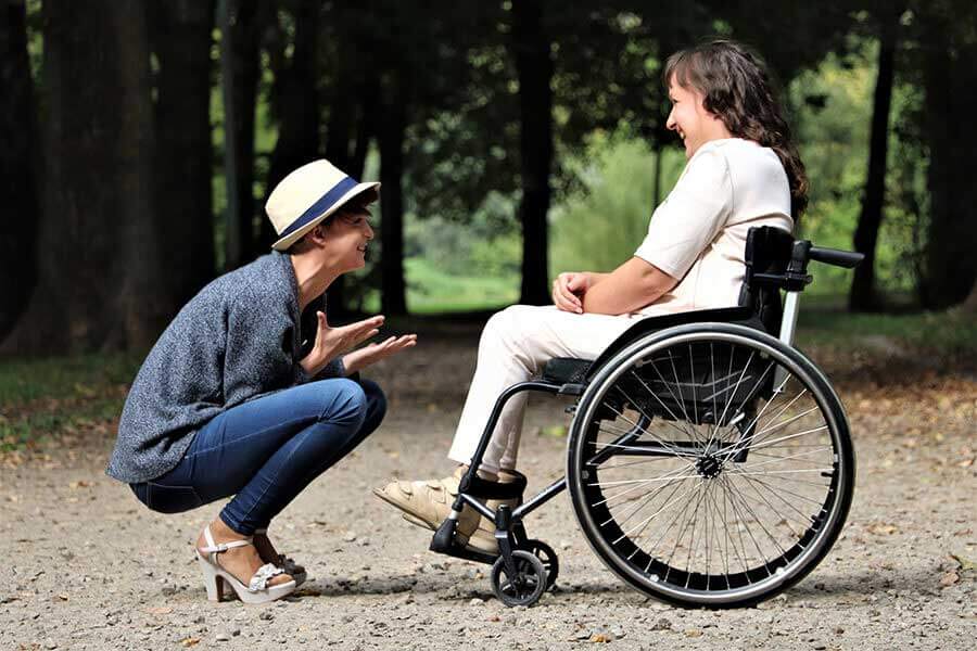 A woman in the park with a woman in a weelchair