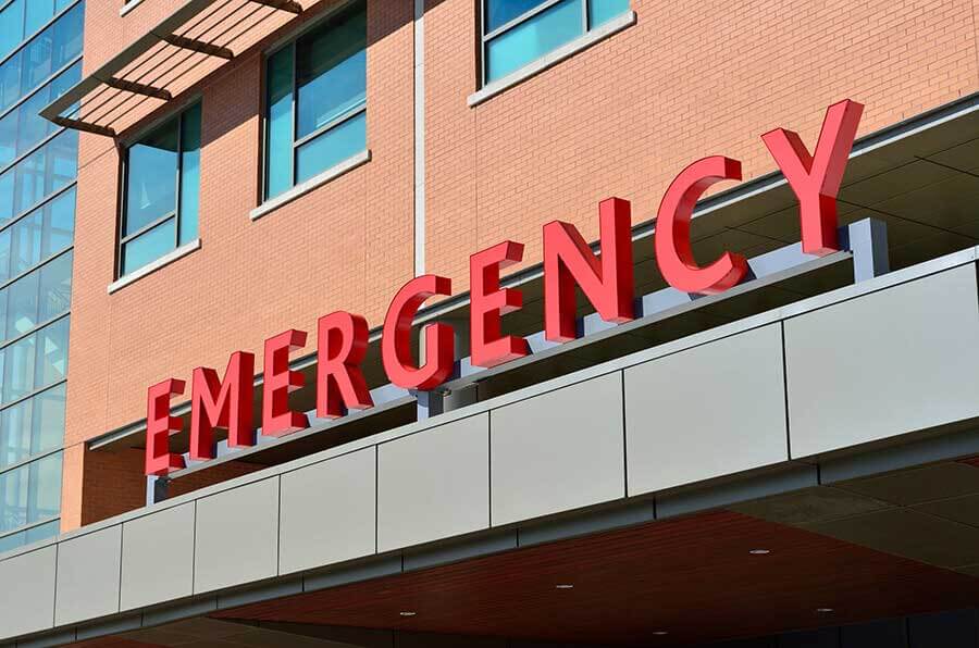 A red Emergency sign over the entrance of a hospital doorway