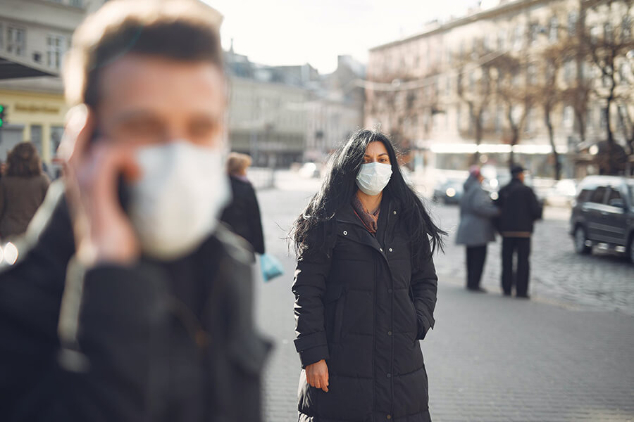 People walking down a city street wearing winter coats and face masks