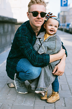 Man hugging a child on a street corner