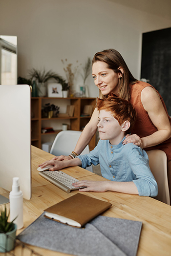 A stay at home parent helping son on the computer