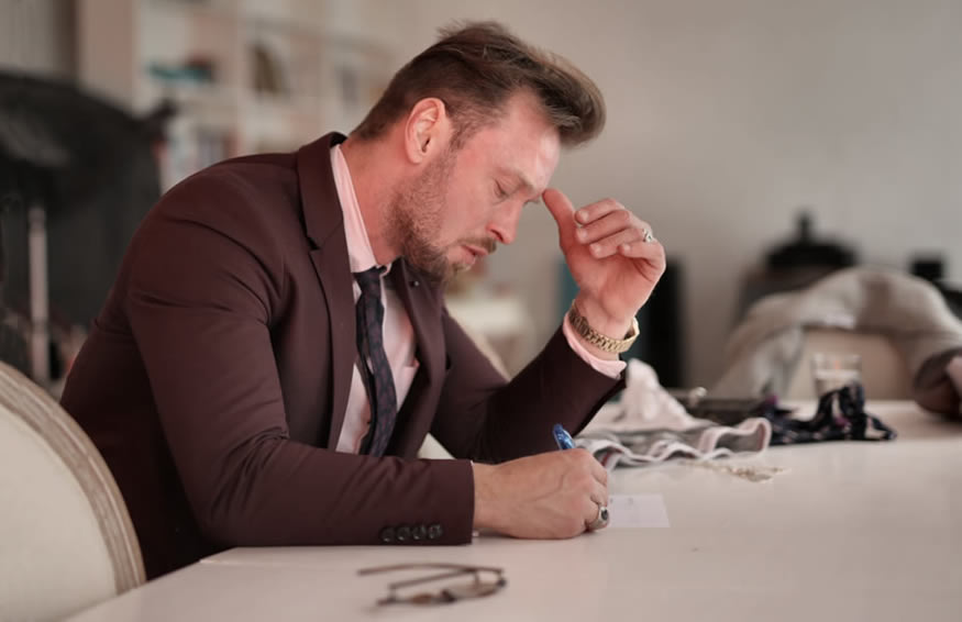 Man focusing as he writes on a piece of paper