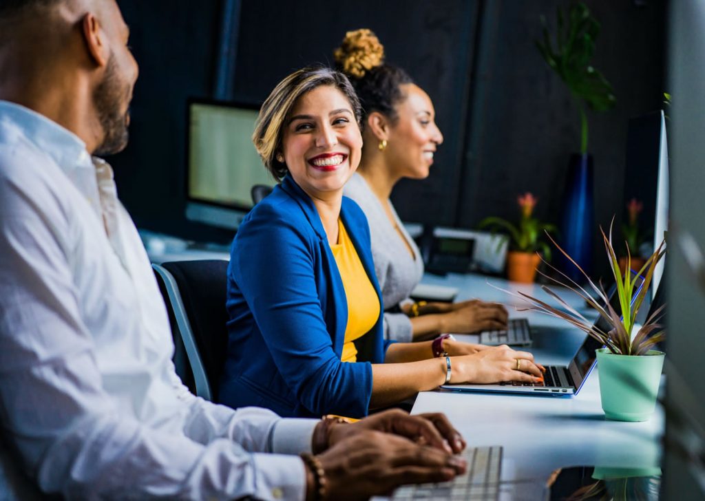 Colleagues smiling while working on their laptops