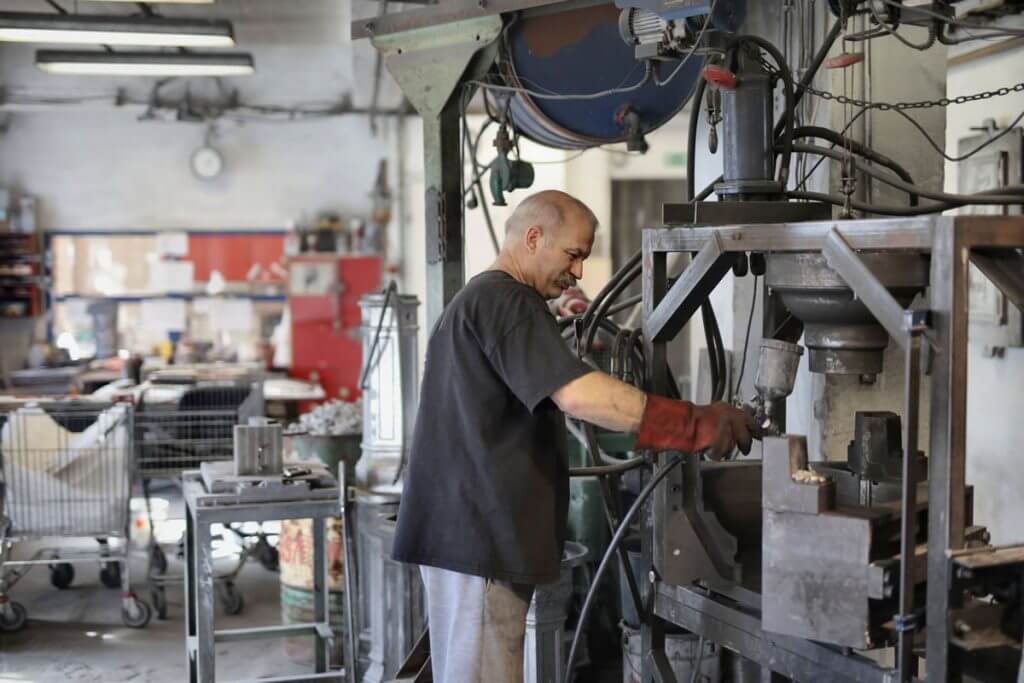 A man repairing a machine in a factory with red gloves