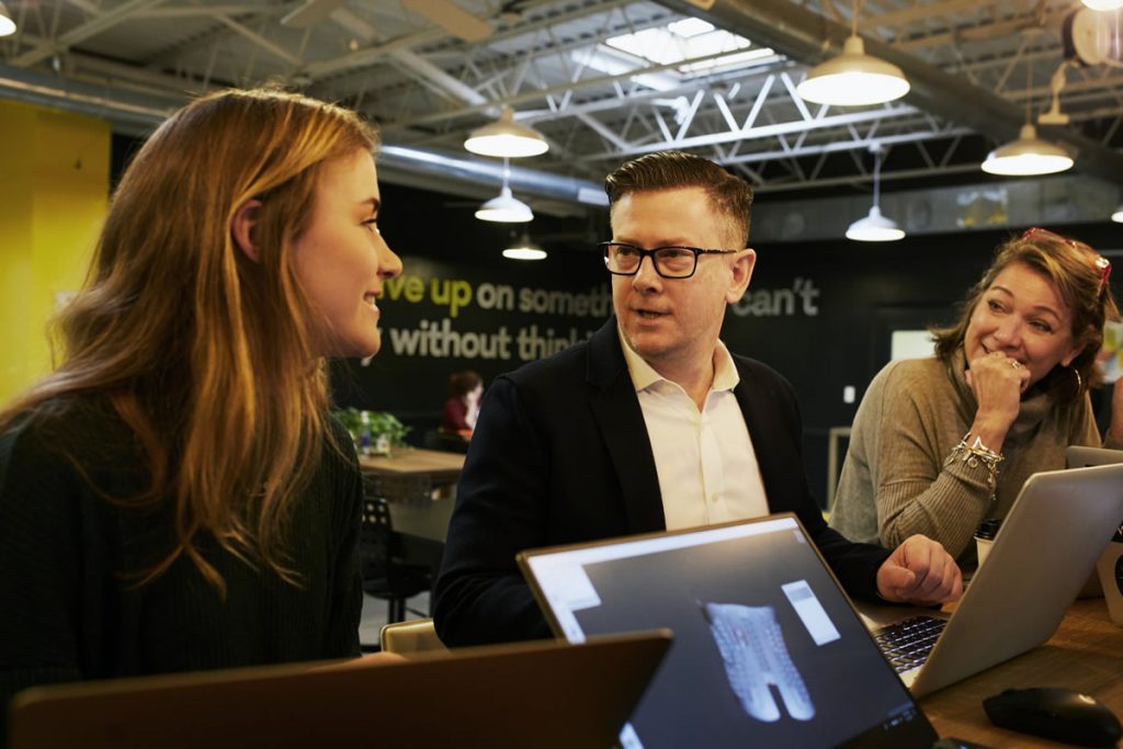 Colleagues discussing finance at a desk with their laptops