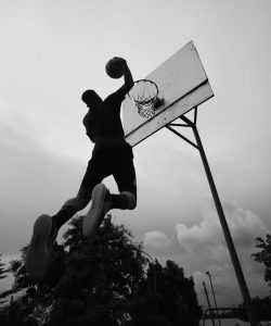 Man playing basketball and making a slam dunk