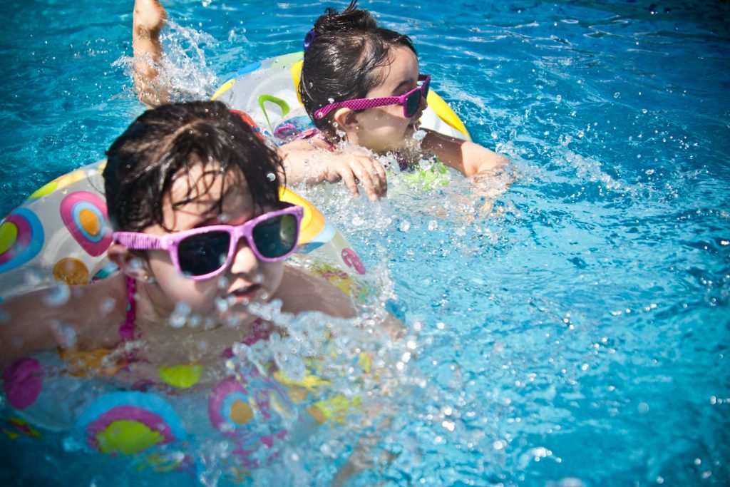 Children swimming in a pool with sunglasses and floaties