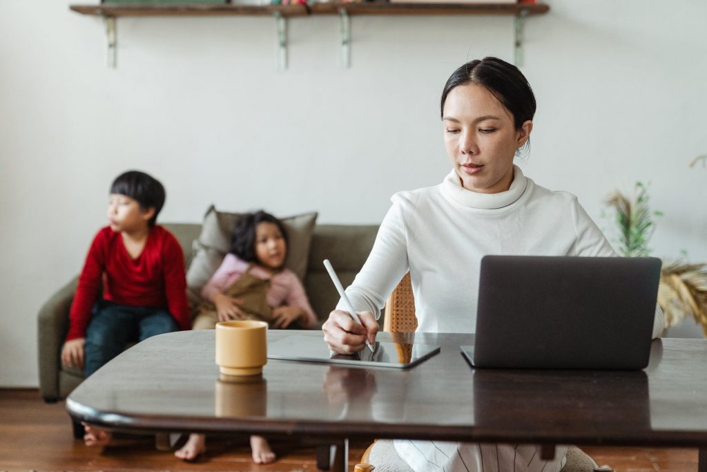 Woman working from home with her children on the couch