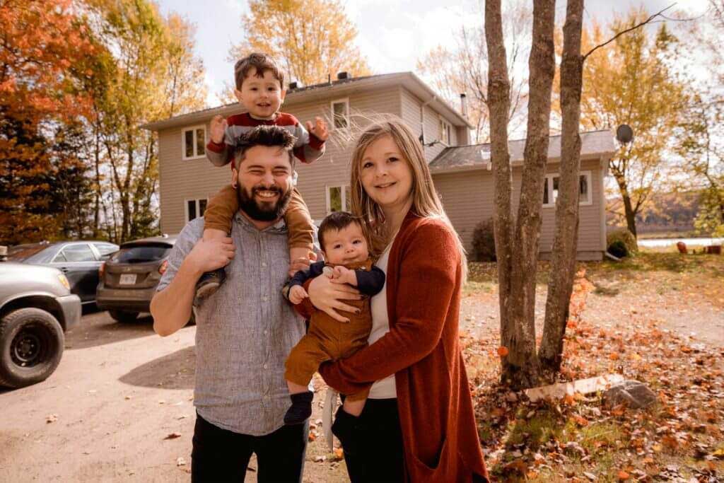 Family in the back yard of their house smiling for a camera