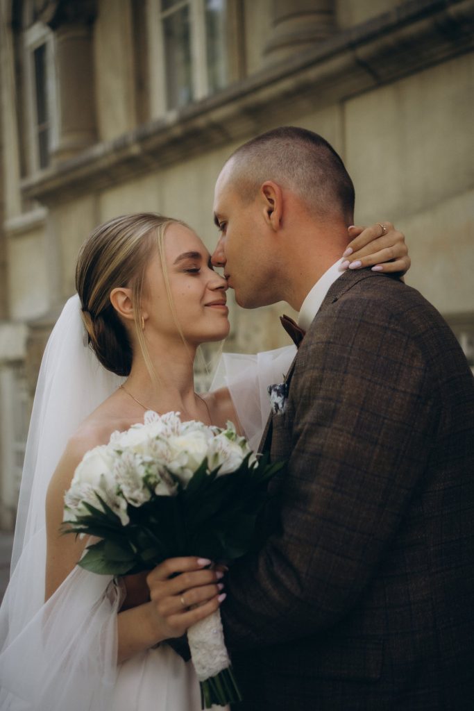 A newlywed couple kissing with a bouquet of flowers