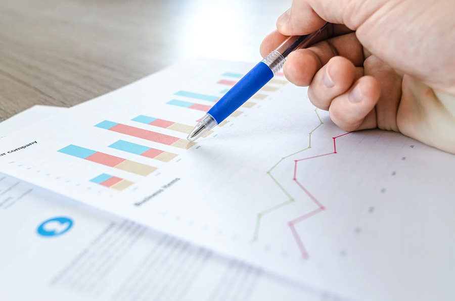 A pen pointing at charts on a white piece of paper