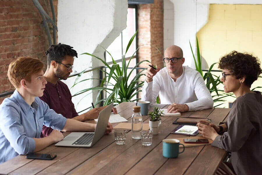 Coworkers communicating around a wooden table with a laptop