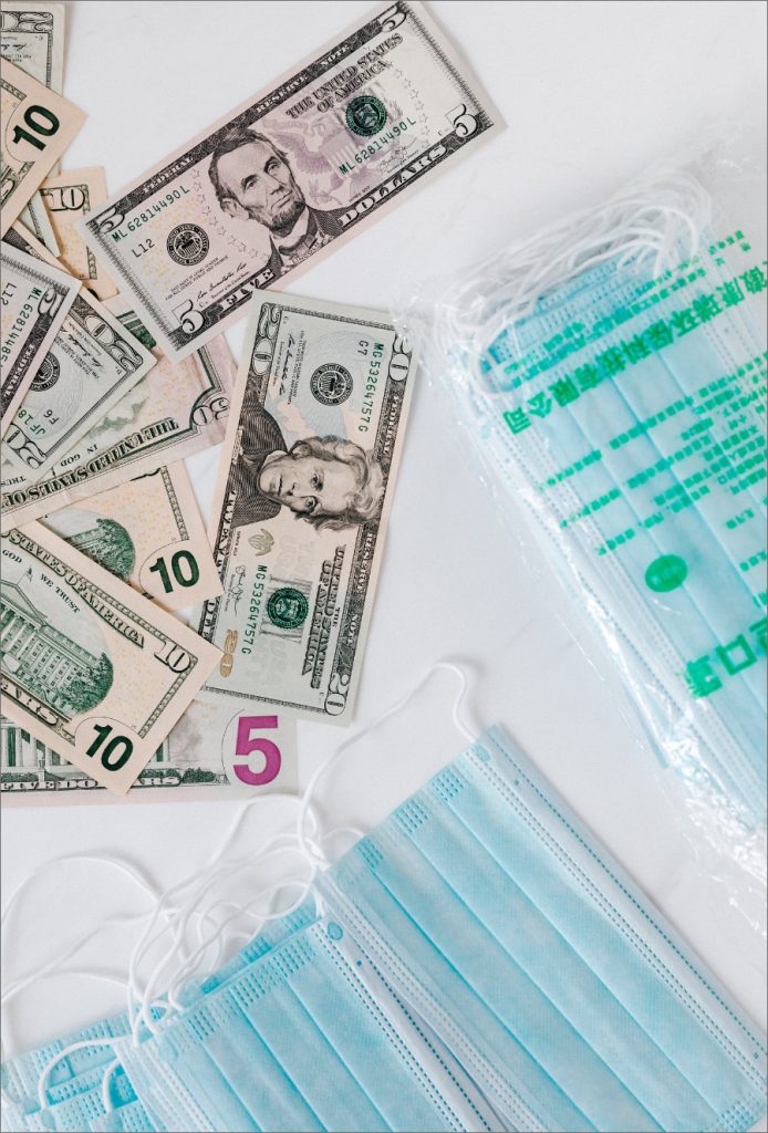 Money and face masks scattered over a white table