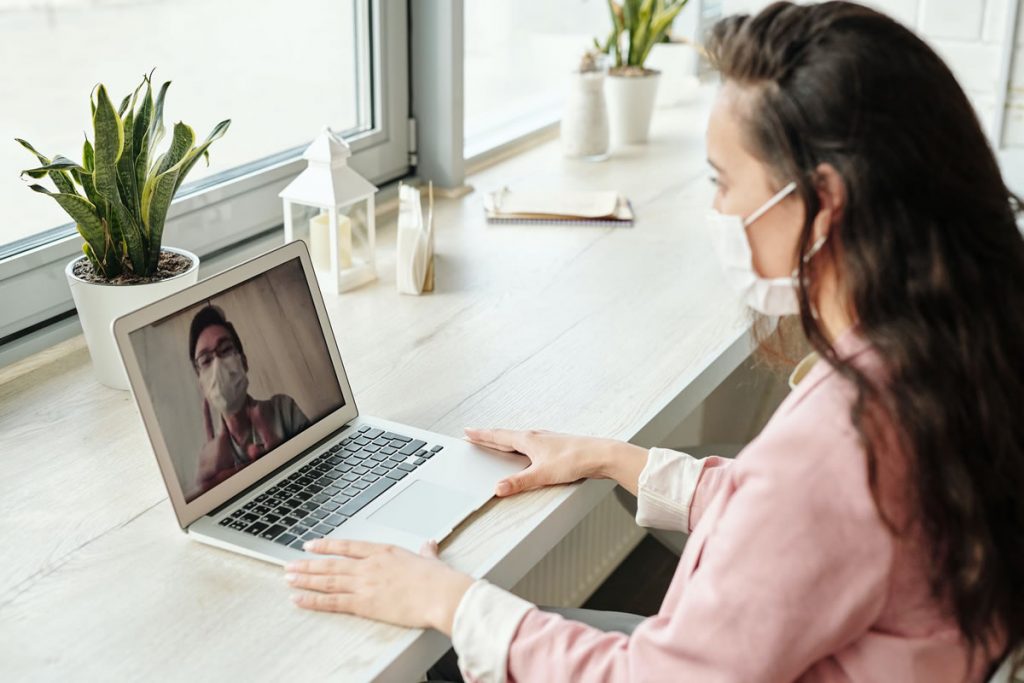 A man and a woman having a video call while wearing face masks