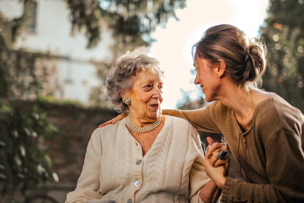 A woman taking her elderly mother for a walk in a park