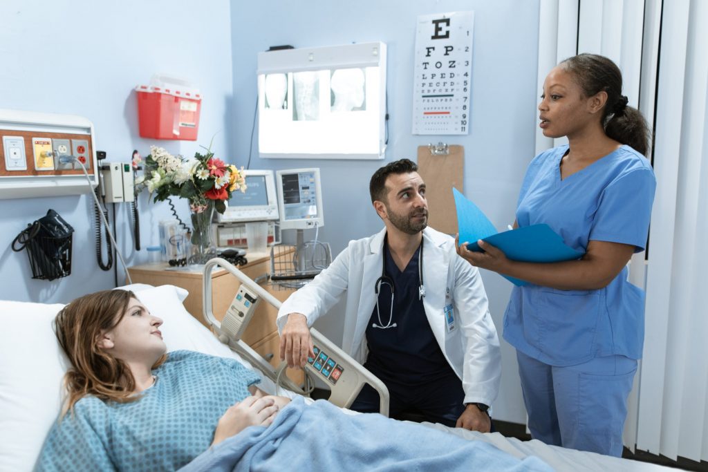 Doctors discussing options with a female patient in a blue hospital room