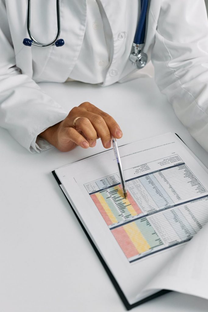 Doctor pointing at data in a notebook over a white desk