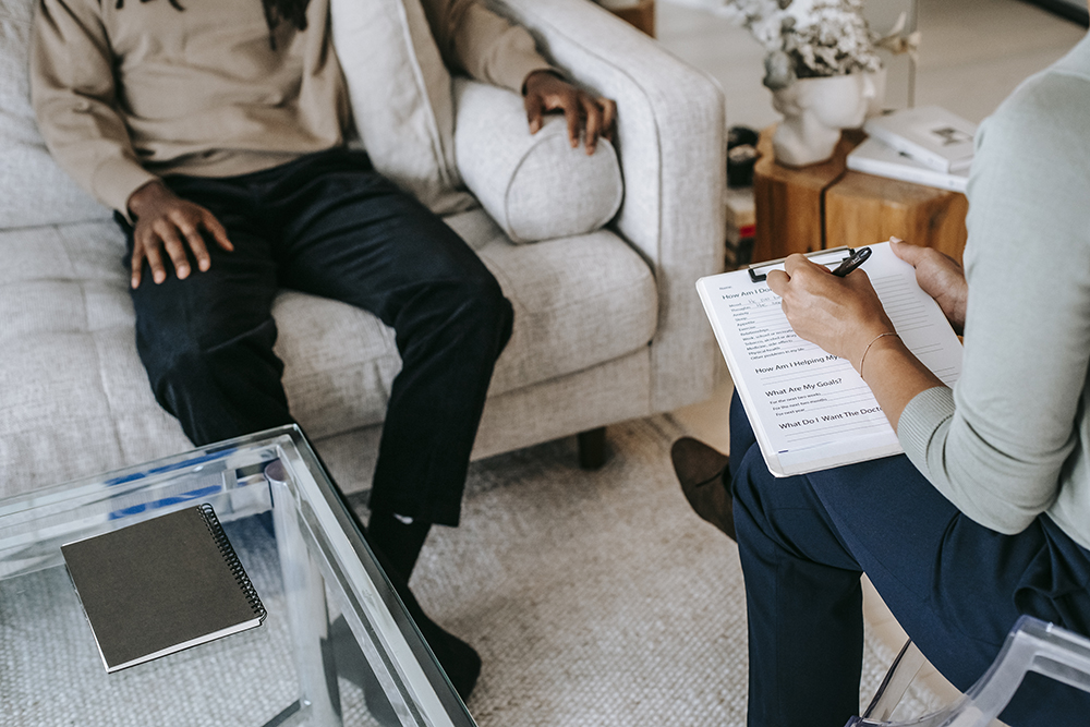 Two people filling out a medical form on a white couch