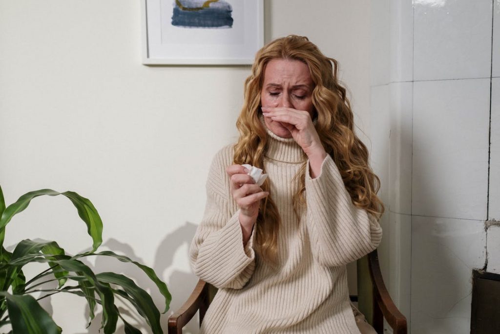 A woman suffering from allergies in a medical office