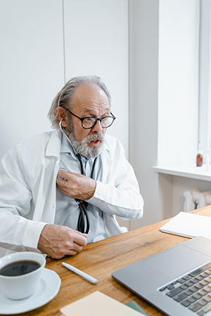 A doctor using a stethoscope on himself while at his desk